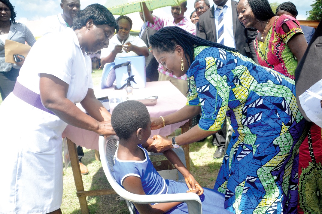 The First Lady (right), administering the vaccine on one of the schoolgirls to launch a campaign against cervical cancer at Dodowa. 