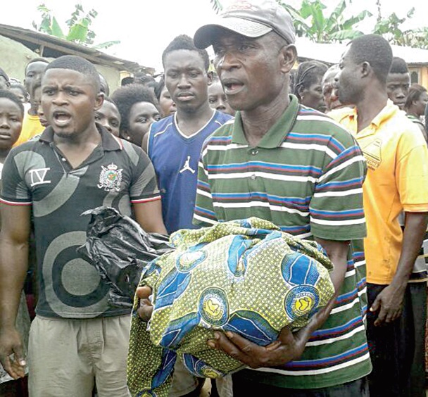 The headless body of the little girl wrapped in a piece of cloth being carried to the hospital by one of her family members.