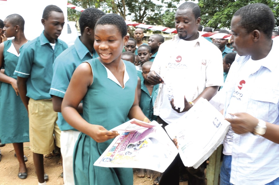 Mr Isaac Okoh (right) of Ad Media, presenting copies of the Junior Graphic to some of the pupils of the Saint Anthony Catholic Basic Schools at Agona Swedru.