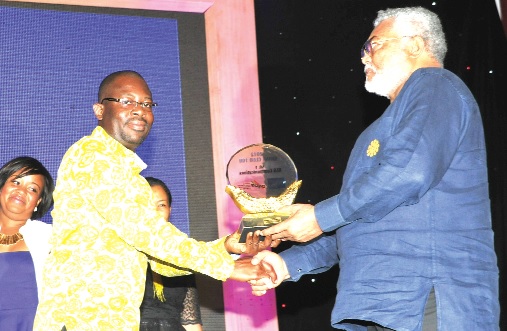 Former President Jerry John Rawlings presenting the number one of Ghana Club 100 best company's award to Roland Ajentumobi, Chief Finance Officer of rlg. 