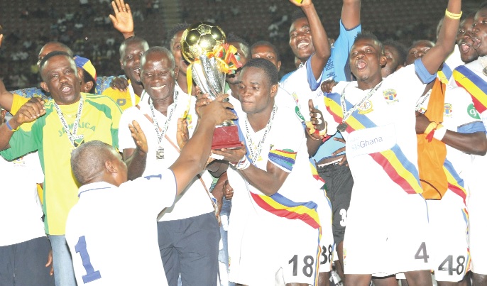 President Mahama hands over the trophy to Hearts captain Mahatma Otoo amidst cheers from his teammates and officials