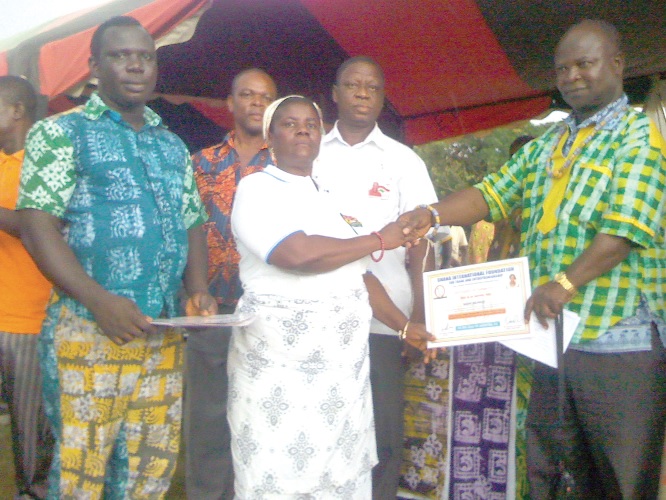 Nana Louis Akattah, the District Chief Executive for Biakoye (right),  presenting a certificate to Madam Grace Teye (middle), one of the participants, while Mr Daniel Antwi, Director of GIFTE (left) looks on.