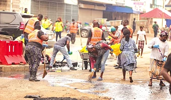 Personnel from Ghana Police Service, Zoomlion Ghana Limited, supported by community members, clearing silt and waste from sections of the road during the cleanup exercise at Accra Central