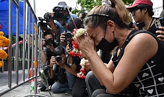 A woman prays for her deceased daughter and her son-in-law